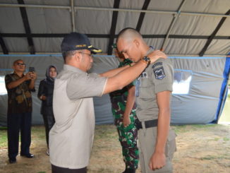 Wakil Bupati Sijunjung, Arrival Boy tengah memasangkan tanda peserta pada pelatihan bela negara