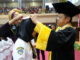 Rektor Ganefri memasangkan cup kepada salah seorang mahasiswa D3 Keperaawatan UNP.