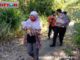 Seorang ibu menggendong bayi yang ditemukan dalam kardus dan Babinkamtibmas mengirigi di belakangnya.
