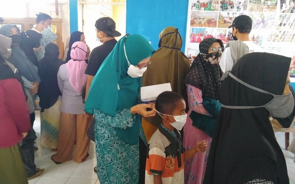 Wakil ketua TP PKK Payakumbuh memasangkan masker kepada anak anak yang ikut mendampingi orang tuanya mengikuti vaksinadi covid 19, tidak memakai masker.