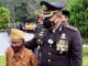 Kapolres Sijunjung, AKBP. Muhammad Ikhwan Lazuardi, S. H, S. Ik, M. H menggandeng seorang veteran menjelang tabur bunga di makam pahlawan Pematang Panjang.