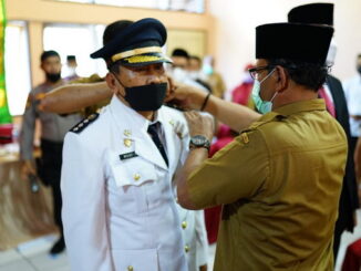 Asisten I Edisar memasangkan tanda pangkat kepada camat yang baru.