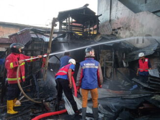 Petugas Damkar Bukittinggi tengah nemadamkan api yang membakar dua unit rumah warga di simpang Baypass.