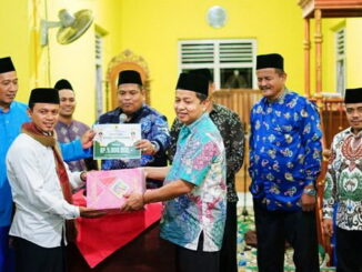 Kabag Kesra Setdakab Drs. Azwarman, MM menyerahkan sumbangan Bupati Suhatri Bur kepada pengurus Masjid Ainul Yaqin dan Camat Nan Sabaris Syamsunar, BA.
