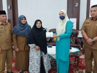 Ny.Piona Erman Safar menyerahkan bantuan kepada warga Kota Bukittinggi yang terlibat hutang kepada rentenir.