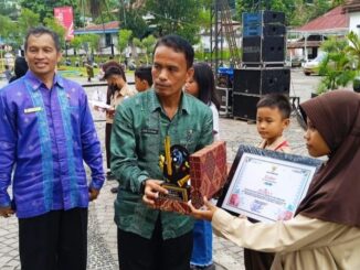 Kepala Dinas Pariwisata Pemuda dan Olahraga Kota Sawahlunto, disaksikan Kepala Dinas Pendidikan saat menyerahkan Piala pada Pemenang Juara 1 Melukis Payung Kote