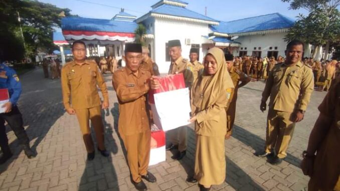 Rusian Heri mewakili Bupati Batu Bara membagikan ribuan Bendera Merah Putih pada apel gabungan ASN.