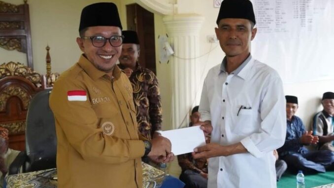 Bupati Eka Putra menyerahkan bantuan pembangunan Masjid Nikmatullah kepada pengurus masjid.