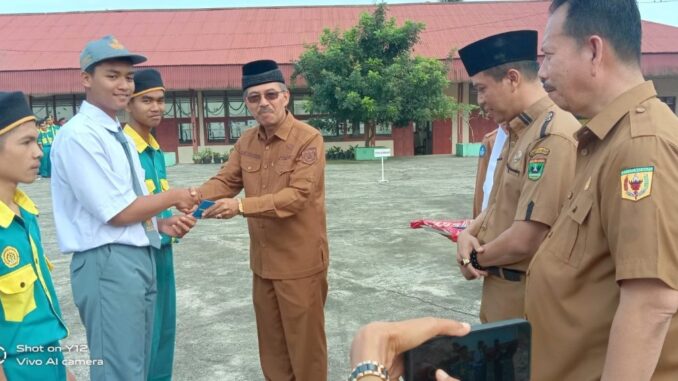 Kepala Disdikbud Tanah Datar Inhendri Abas menyerahkan hadiah ulang tahun untuk siswa dari Bupati Eka Putra E KTP Elekronik disaksikan oleh Kepala Dinas Dukcapil Harmen Yudhi.